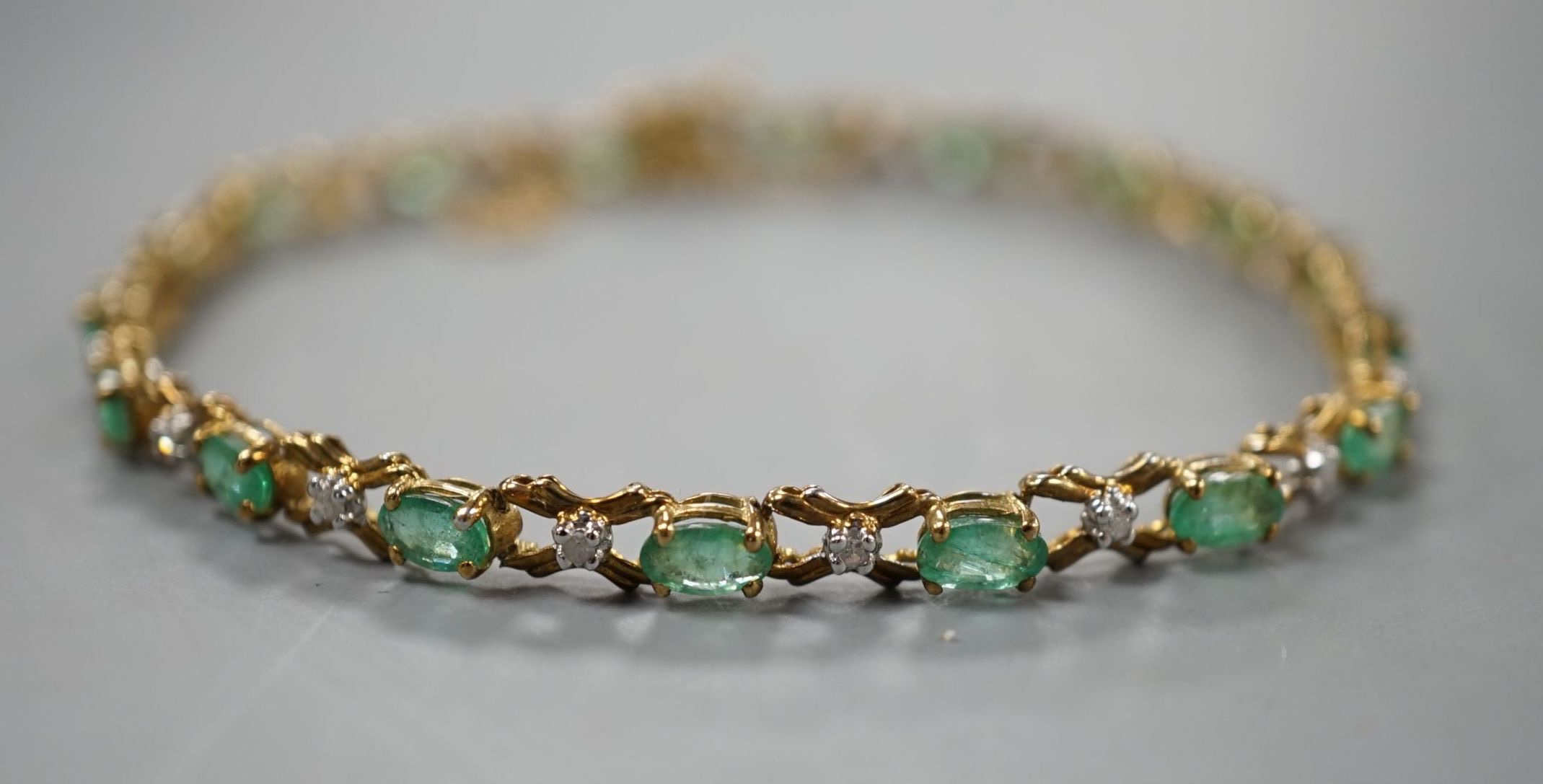 A modern 9ct gold, emerald and diamond chip set line bracelet, approx. 17cm, gross weight 5 grams.